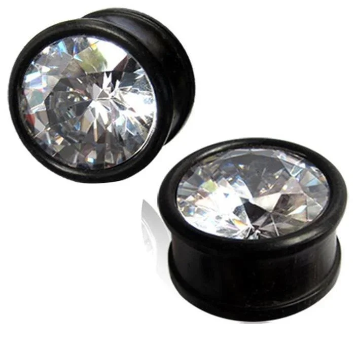 A pair of hand-carved Kristallplug Eisenholz schwarz Holzplugs with large, round, clear rhinestone fronts that sparkle and reflect light.