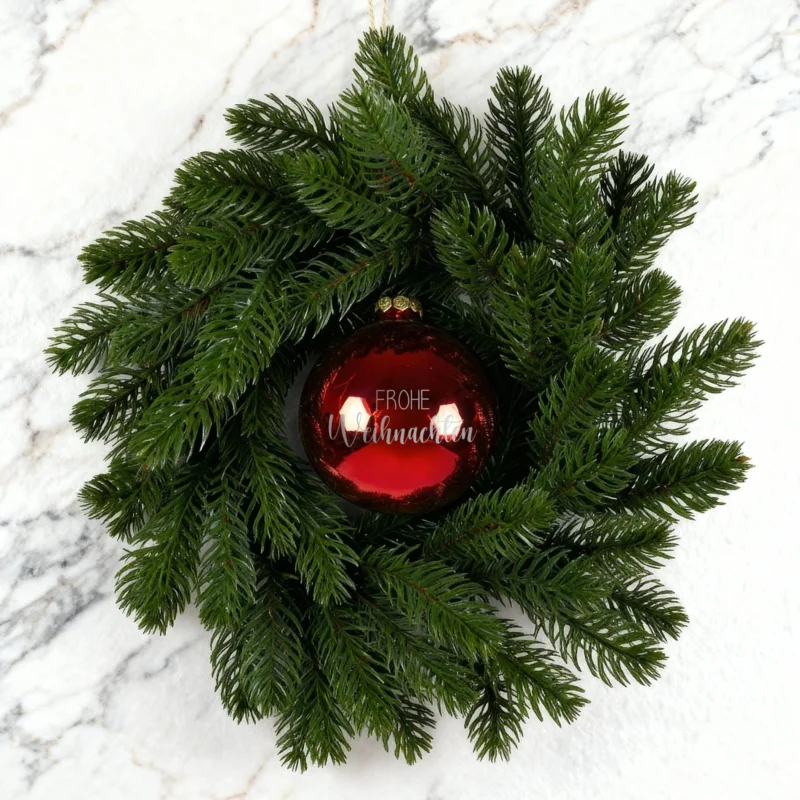 Weihnachtskranz mit roter Kugel Frohe Weihnachten auf weiß-marmoriertem Hintergrund